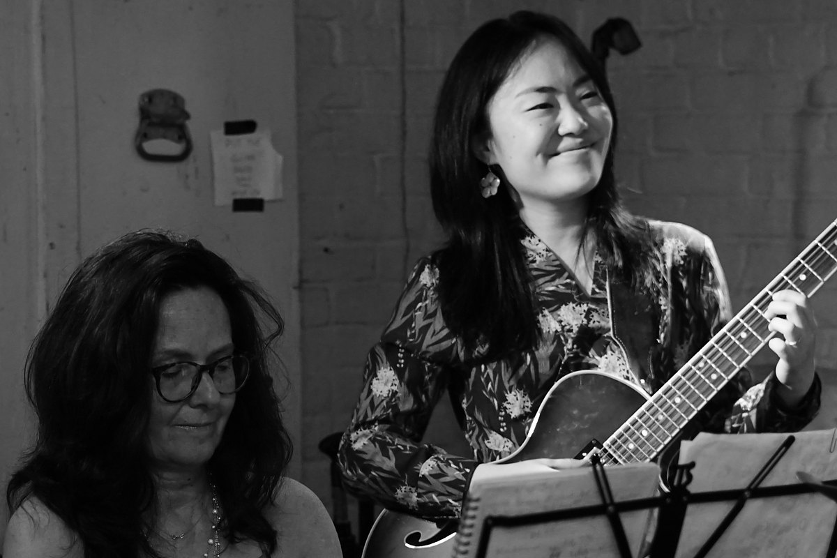 Two musicians playing piano and archtop guitar in the studio, reading from charts